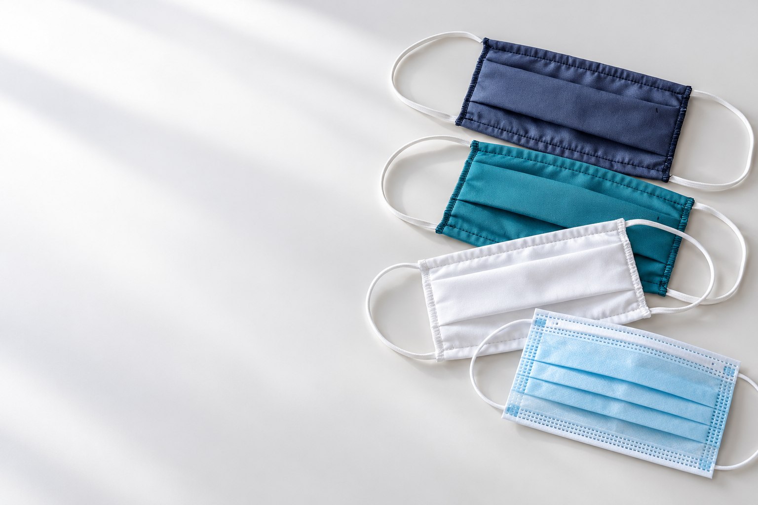 Masques en tissu et masques à usage unique présentés sur un fond clair